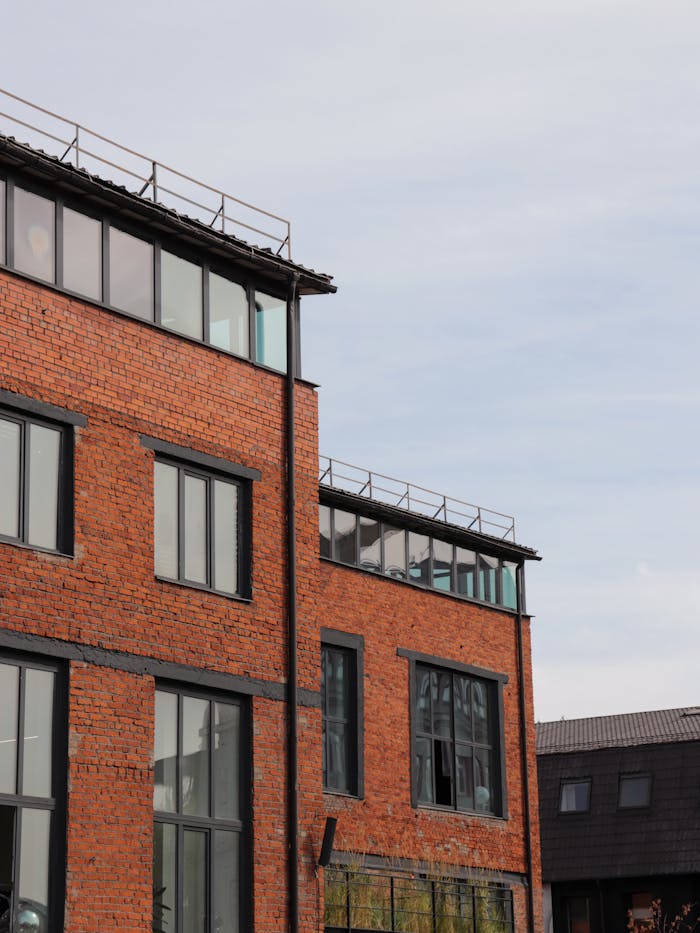 services-01 Contemporary architecture featuring a red brick facade with large glass windows and a clear sky.