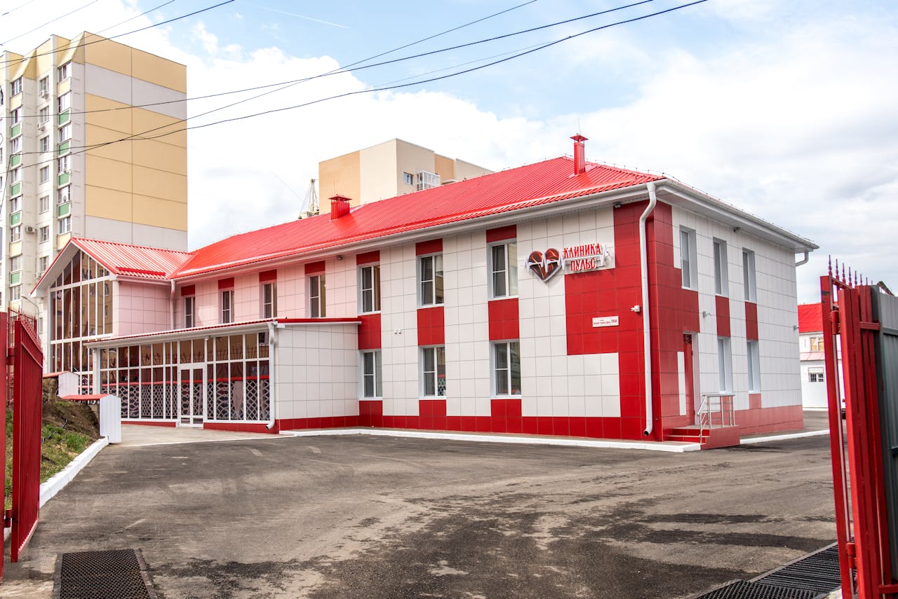 gallery-4 Modern clinic building with red and white facade, showcasing contemporary architecture.