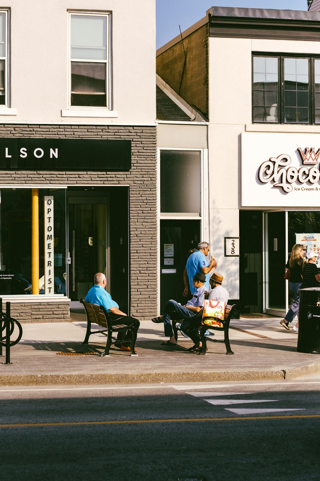 services-03 people-sitting-on-benches-outside-shops-on-a-sunny-day-3-w11uf9j4i